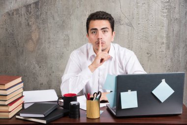 Genç ofis çalışanı ofis masasında sessizlik işareti yapıyor. Yüksek kalite fotoğraf