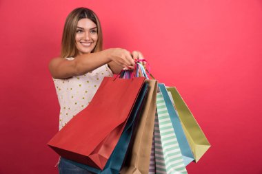 Kırmızı arka planda alışveriş torbaları gösteren bir kadın. Yüksek kalite fotoğraf