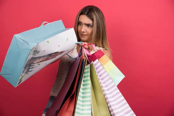 Een Vrouw Die Haar Boodschappentassen Kijkt Een Rode Achtergrond Hoge — Stockfoto