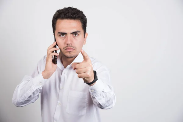 Geschäftsmann Spricht Mit Handy Und Zeigt Auf Kamera Auf Weißem — Stockfoto