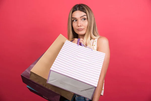 Mujer Llevando Bolsas Compras Con Expresión Neutra Sobre Fondo Rojo —  Fotos de Stock