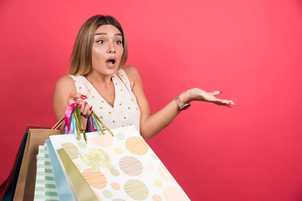 Frau Mit Einkaufstaschen Mit Schockiertem Gesichtsausdruck Auf Rotem Hintergrund Hochwertiges — Stockfoto