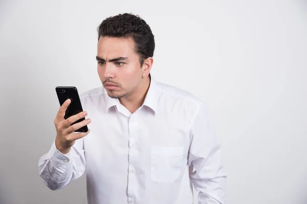 Geschäftsmann Schaut Intensiv Auf Telefon Auf Weißem Hintergrund Hochwertiges Foto — Stockfoto