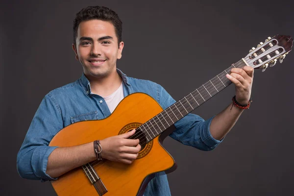 暗い背景でギターを弾く笑顔の男 高品質の写真 — ストック写真