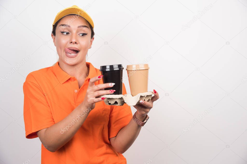 Blonde female courier holding two cups of coffees on white background. High quality photo