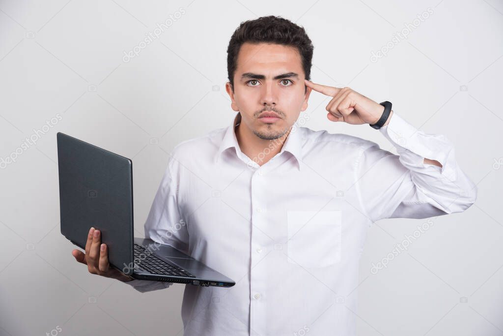 Businessman with laptop pointing at his head on white background. High quality photo