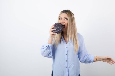 Mavi kıyafetli güzel bir kadın beyaz arka planda mor lahana yiyor. Yüksek kalite fotoğraf