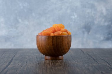 Ahşap bir masada sağlıklı kurutulmuş kayısı meyveleriyle dolu bir kase. Yüksek kalite fotoğraf