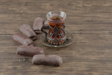 Tahta bir masanın üzerinde çikolata çubukları olan bir bardak lezzetli sıcak çay. Yüksek kalite fotoğraf