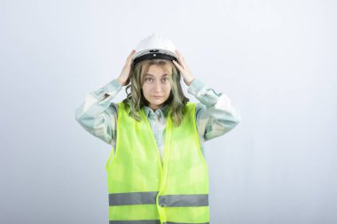 Beyaz arka planda duran yeşil yelekli genç inşaat işçisinin fotoğrafı. Yüksek kalite fotoğraf