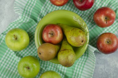 Mermer yüzeyde taze elma ve armut dolu yeşil kase. Yüksek kalite fotoğraf