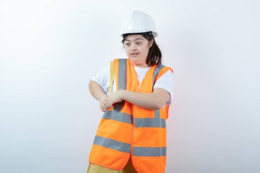 Beyaz duvarın üzerinde duran kasklı genç bayan inşaat işçisi. Yüksek kalite fotoğraf