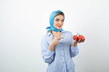 Mavi şallı genç bir kadının fotoğrafı elindeki kırmızı domatesleri gösteriyor. Yüksek kalite fotoğraf