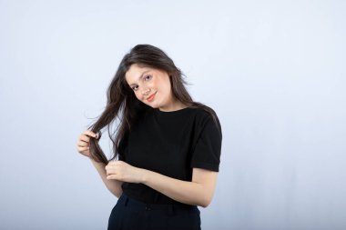 Siyah bluzlu esmer bir kızın beyaz duvardan kameraya baktığı görüntü. Yüksek kalite fotoğraf