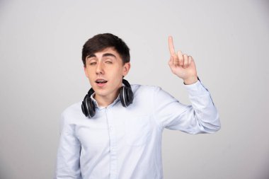 Kulaklıklı genç yakışıklı adamın bir yeri işaret ettiği bir fotoğraf. Yüksek kalite fotoğraf