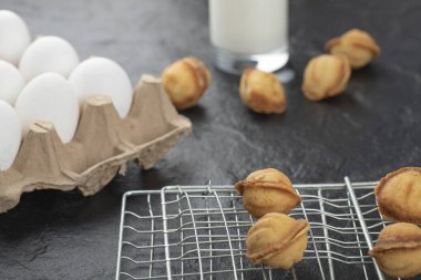 Ceviz şeklinde taze kurabiyeler ve siyah arka planda yumurta ve süt. Yüksek kalite fotoğraf