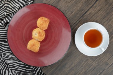 Kırmızı tabak lezzetli kadaif hamur işleri ve tahta masada bir fincan çay. Yüksek kalite fotoğraf