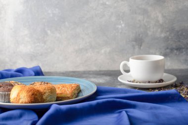 White cup of hot black tea with sweet snacks placed on stone table. High quality photo