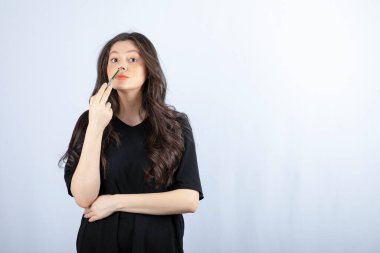 Güzel genç bir kadın burnuna kozmetik fırçasıyla fosforlu kalem koyuyor. Yüksek kalite fotoğraf