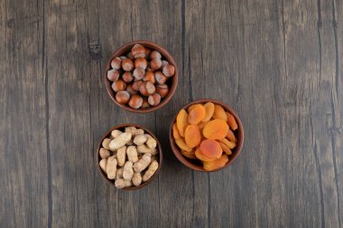 Tahta masada kurutulmuş kayısı meyveleri ve sağlıklı fındıklarla dolu tahta kaseler. Yüksek kalite fotoğraf