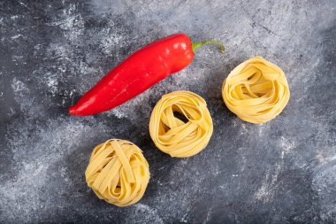 Mermer yüzeyinde kırmızı biberli çiğ makarna yuvaları. Yüksek kalite fotoğraf