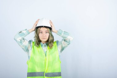 Beyaz fonda duran beyaz şapkalı genç inşaat işçisinin görüntüsü. Yüksek kalite fotoğraf