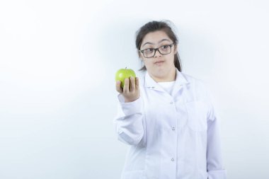 Elinde yeşil elma tutan doktor üniformalı genç bir kız. Yüksek kalite fotoğraf