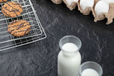 Siyah arka planda kurabiyeli iki süt şişesi ve yumurta. Yüksek kalite fotoğraf