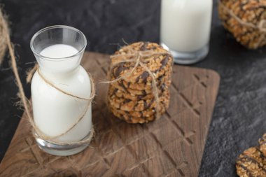 Tahta kesme tahtasının üzerinde kurabiye yığını olan bir şişe sütün yakın fotoğrafını çek. Yüksek kalite fotoğraf