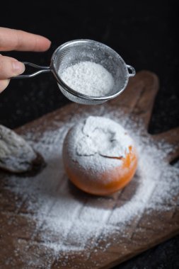 Tahta bir tahtanın üzerinde olgun bir hurma ağacına şeker tozu serpiştiren bir kadın. Yüksek kalite fotoğraf