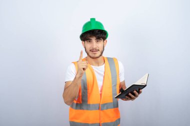 Yeşil şapkalı genç erkek mühendis beyaz arka plandaki projesinden bahsediyor. Yüksek kalite fotoğraf