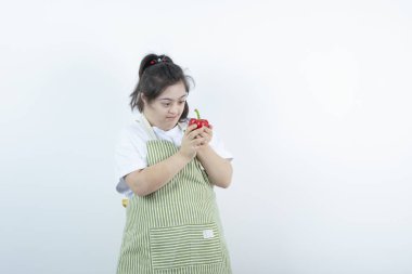 Kareli önlük giymiş genç ve güzel bir kız kırmızı dolmalık bibere bakıyor. Yüksek kalite fotoğraf