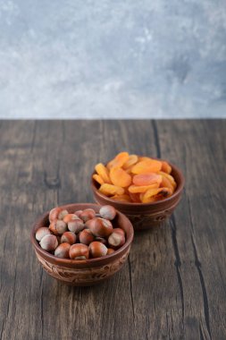 Tahta masada kurutulmuş kayısı meyveleri ve sağlıklı fındıklarla dolu tahta kaseler. Yüksek kalite fotoğraf