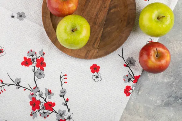 Mermer yüzeyde taze kırmızı ve yeşil elmalardan oluşan ahşap bir tabak. Yüksek kalite fotoğraf