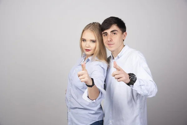 カメラで指を指す若いカップルの肖像画灰色の背景の上に隔離された 高品質の写真 — ストック写真