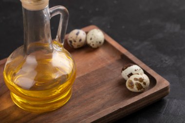 Pişmemiş organik bıldırcın yumurtaları ve tahta kesme tahtasının üzerinde bir şişe zeytin yağı. Yüksek kalite fotoğraf