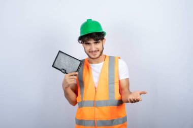 Yeşil şapkalı genç mühendis elinde siyah defter ve ayakta duruyor. Yüksek kalite fotoğraf