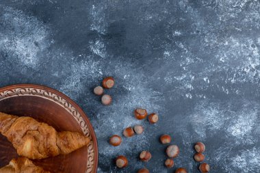 Taze kruvasan ve sağlıklı macadamia fındıklı yuvarlak bir tabak. Yüksek kalite fotoğraf