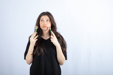 Beyaz arka planda yanaklarına allık süren genç bir kızın portresi. Yüksek kalite fotoğraf