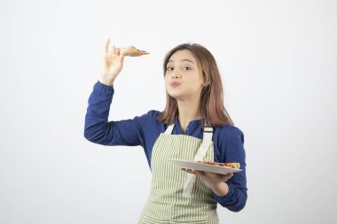 Genç bayan aşçının portresi. Elinde lezzetli bir pizza tabağı var. Yüksek kalite fotoğraf