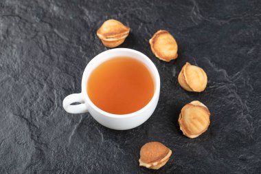 Ceviz şeklinde kurabiyeler ve siyah arka planda bir fincan sıcak çay. Yüksek kalite fotoğraf