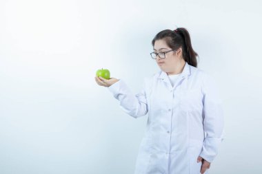 Elinde yeşil elma tutan doktor üniformalı genç bir kız. Yüksek kalite fotoğraf
