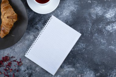 Mermer bir arka planda boş bir defter ile beyaz bir fincan sıcak çay. Yüksek kalite fotoğraf