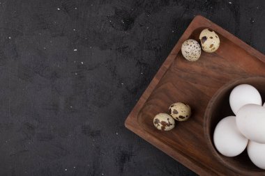 Pişmemiş organik bıldırcın ve tahta kesme tahtasının üzerinde bir kase tavuk yumurtası. Yüksek kalite fotoğraf