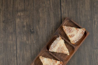 Tahta masa üzerinde hindistan cevizi parçacıkları serpiştirilmiş ahşap pasta dilimleri. Yüksek kalite fotoğraf