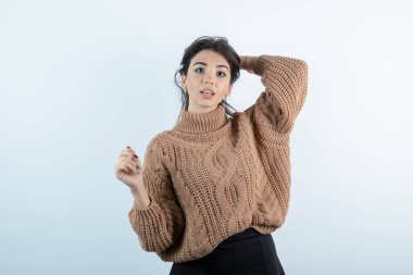 Beyaz duvarın üzerinde kameraya poz veren örgü elbiseli güzel bir kadının portresi. Yüksek kalite fotoğraf