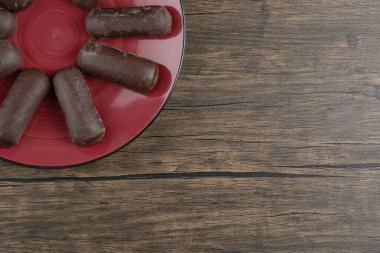 Süt kremalı çikolatalı rulo ile dolu kırmızı bir tabak. Yüksek kalite fotoğraf