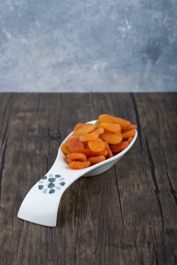 Tahta bir masada sağlıklı kurutulmuş kayısı meyveleriyle dolu bir kaşık. Yüksek kalite fotoğraf