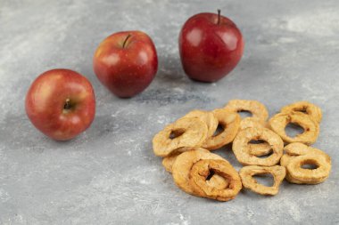 Taze kırmızı elmalar ve mermer zemin üzerinde kurumuş halkalar. Yüksek kalite fotoğraf