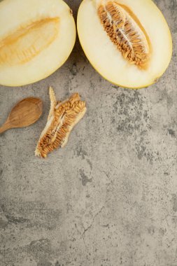 Ahşap kaşıkla mermer yüzeyde yarım lezzetli sarı kavunlar. Yüksek kalite fotoğraf